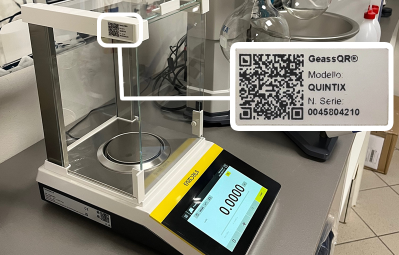 Bilancia elettronica da laboratorio con schermo digitale e involucro in vetro trasparente, su piano di lavoro.